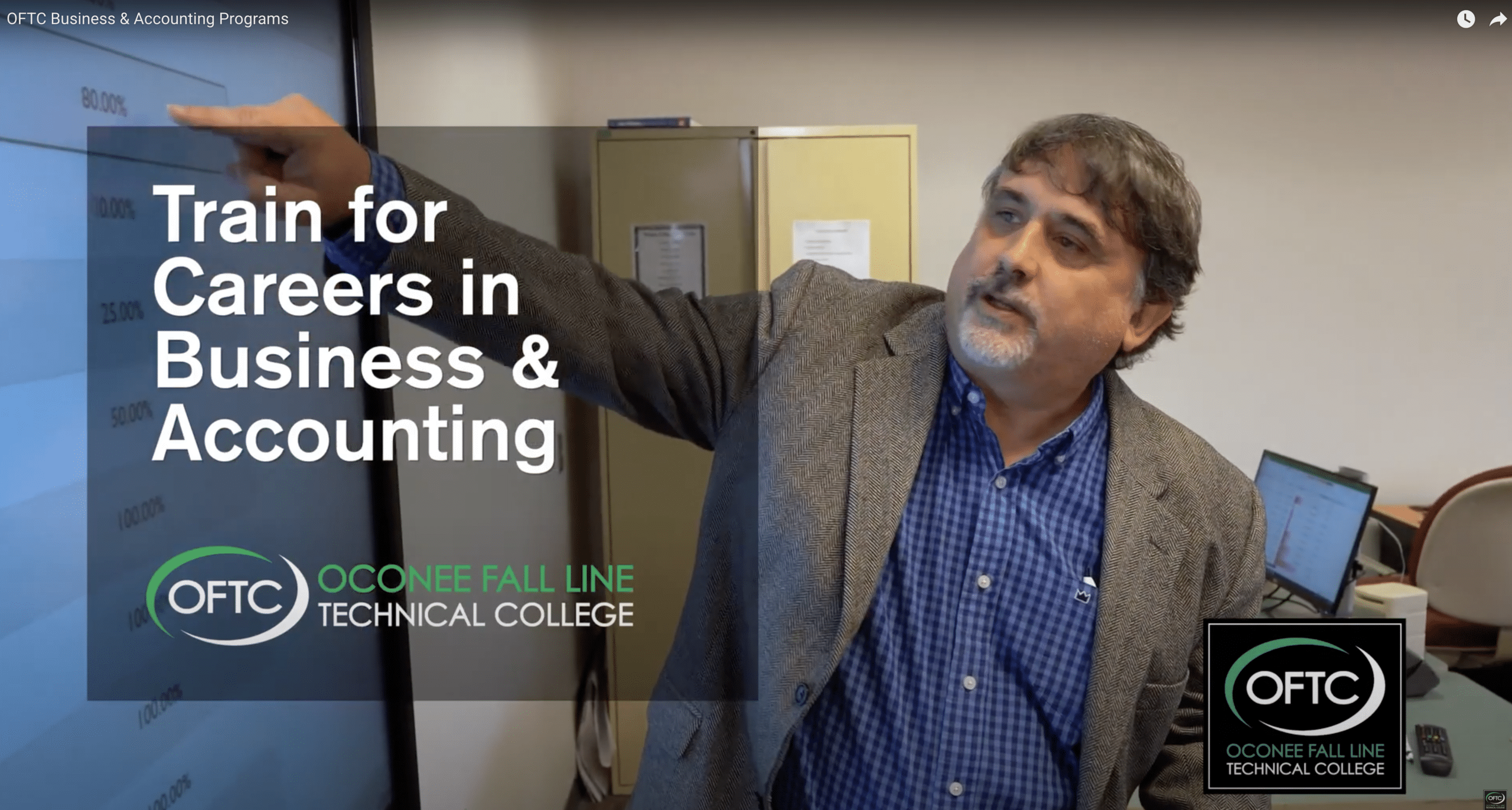 A man in a suit points at a large screen in an office. Text overlay reads, Train for Careers in Business & Accounting. The OFTC Oconee Fall Line Technical College logo appears in the bottom left and right corners.