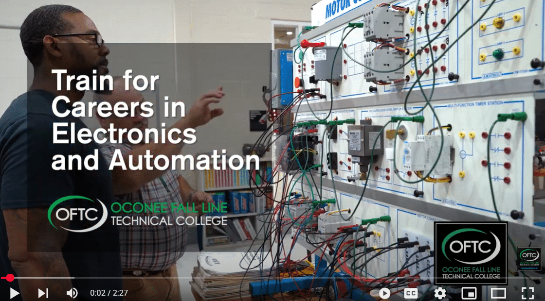 A man gestures toward a wall-mounted electronics and automation training board with various wires and components at Oconee Fall Line Technical College. Text reads: Train for Careers in Electronics and Automation.