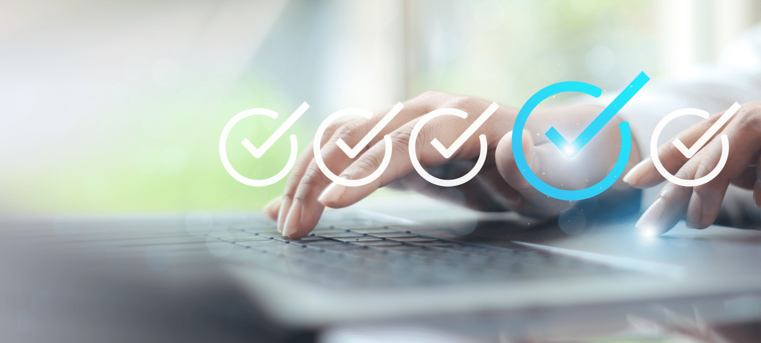 A person typing on a laptop keyboard with translucent check mark icons above; the last check mark is blue, indicating task completion.