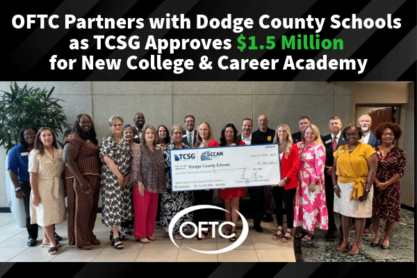 A group of people stands together in business attire, holding an oversized check for $1.5 million. Above them, text announces a partnership to launch a new college and career academy. The OFTC and TCSG logos are visible.