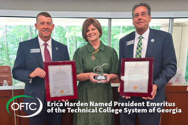 Three people stand indoors smiling; the woman in the center holds a trophy, while the two men on either side hold framed certificates. Text reads: Erica Harden Named President Emeritus of the Technical College System of Georgia.